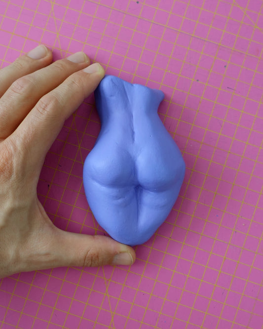 A beautiful handmade figurine depicting a female butt, coloured using lilac acrylics.